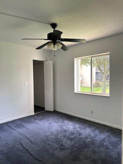 carpeted spare room with ceiling fan and a textured ceiling