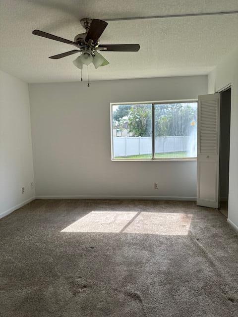 carpeted spare room with ceiling fan and a textured ceiling