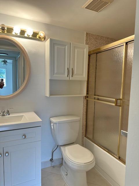 full bathroom with tile patterned flooring, bath / shower combo with glass door, vanity, and toilet