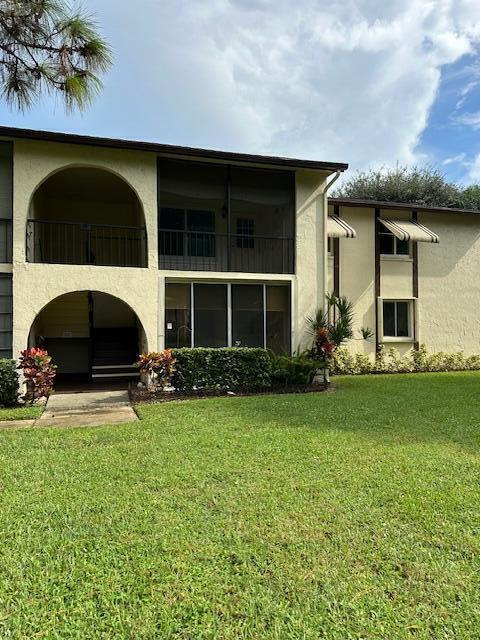 rear view of property with a balcony and a lawn