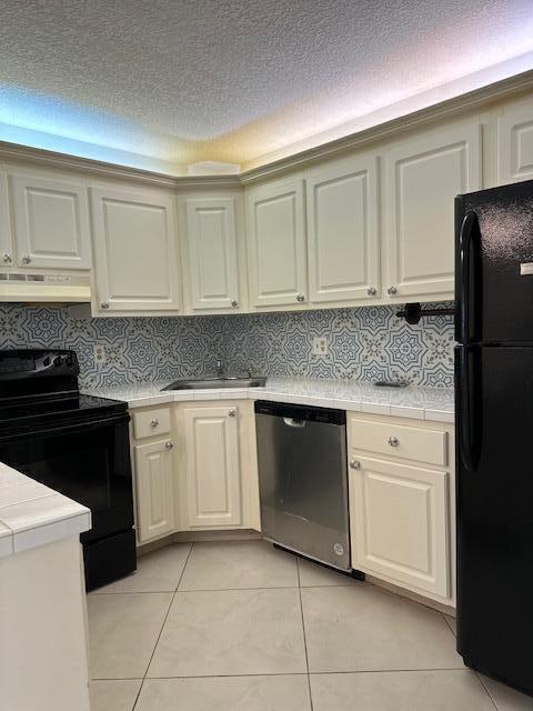 kitchen with range hood, black appliances, tile counters, and light tile patterned flooring