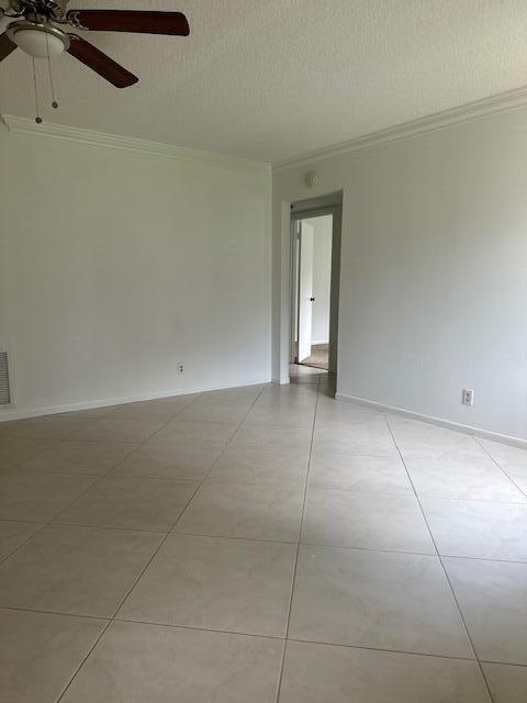 tiled empty room with a textured ceiling, crown molding, and ceiling fan