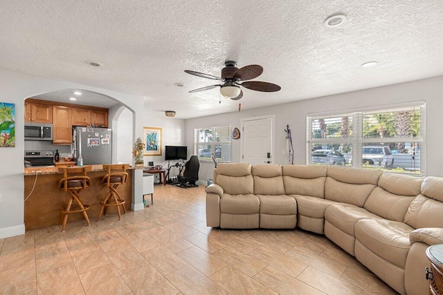 tiled living room featuring ceiling fan and a textured ceiling