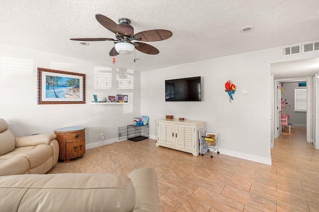 living room featuring ceiling fan and a textured ceiling