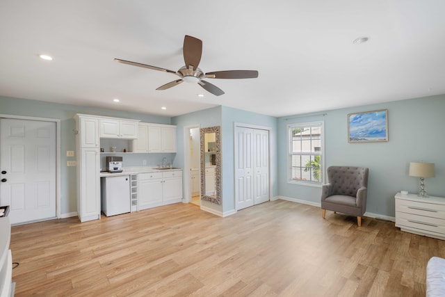 kitchen with light hardwood / wood-style floors, ceiling fan, white dishwasher, and white cabinets