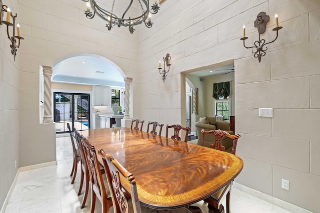 dining room with tile walls, decorative columns, and a high ceiling