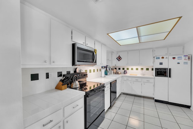 kitchen featuring black appliances, tasteful backsplash, tile counters, and white cabinets