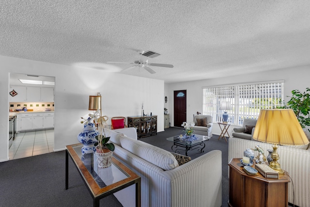 living room with ceiling fan, light tile patterned flooring, and a textured ceiling