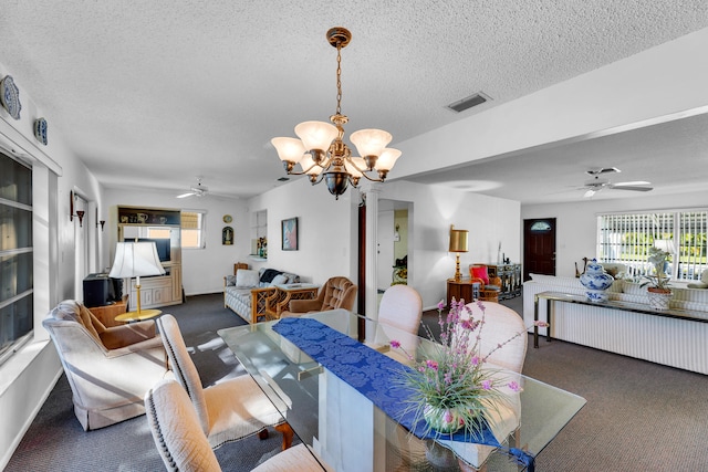 dining area featuring a textured ceiling, ceiling fan with notable chandelier, and dark colored carpet