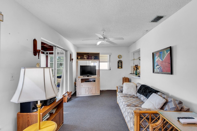 carpeted living room featuring ceiling fan and a textured ceiling