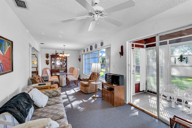 living room featuring ceiling fan with notable chandelier, a textured ceiling, and carpet flooring