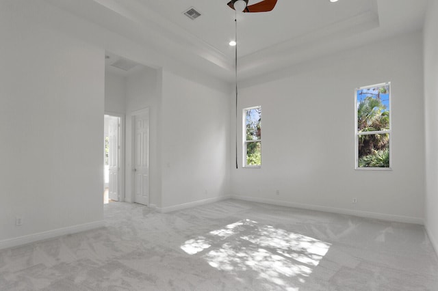 carpeted spare room featuring crown molding, a tray ceiling, and ceiling fan