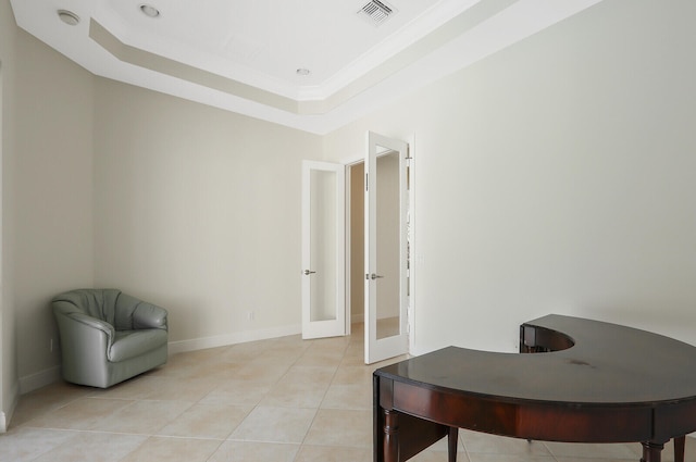 office space with a tray ceiling and light tile patterned floors