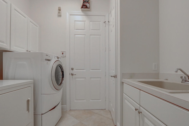 washroom with washing machine and dryer, sink, light tile patterned floors, and cabinets