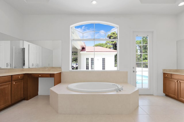 bathroom with tile patterned flooring, tiled tub, and vanity