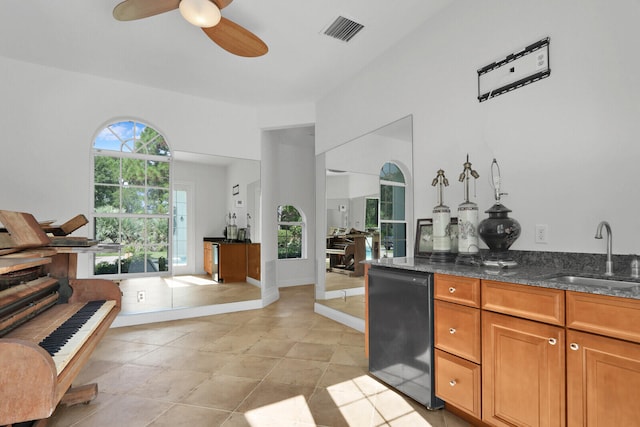 interior space with dark stone countertops, light tile patterned flooring, sink, and ceiling fan