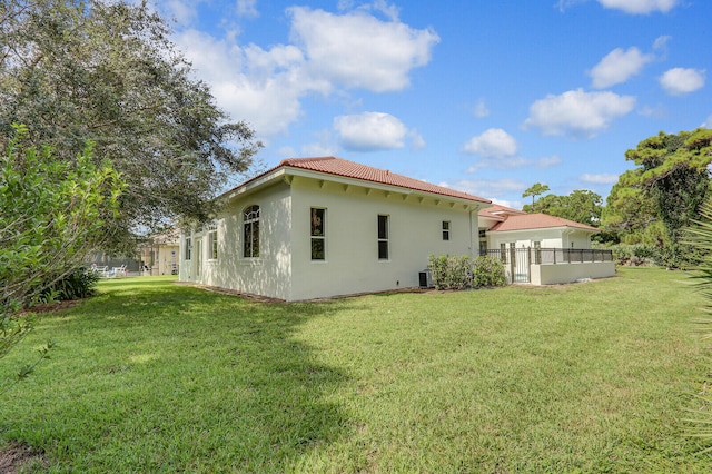 rear view of house featuring a lawn and central AC unit