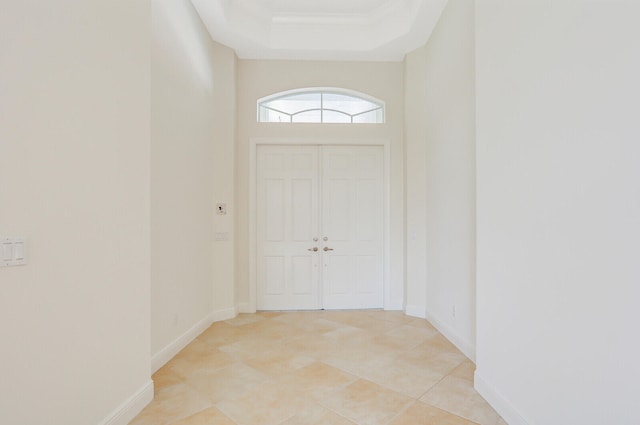 doorway to outside with a tray ceiling and light tile patterned floors