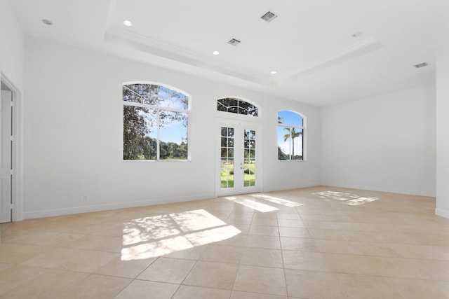 empty room featuring french doors, a raised ceiling, and light tile patterned floors