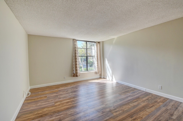 spare room with a textured ceiling and dark hardwood / wood-style flooring