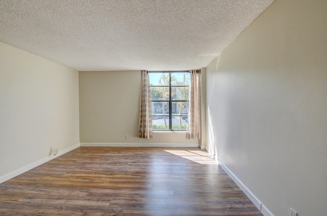 spare room with a textured ceiling and dark hardwood / wood-style floors