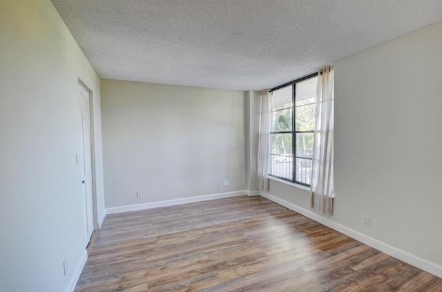 unfurnished room with a textured ceiling and light hardwood / wood-style flooring