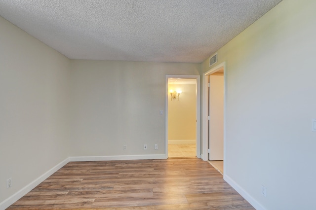 unfurnished room featuring a textured ceiling and light wood-type flooring