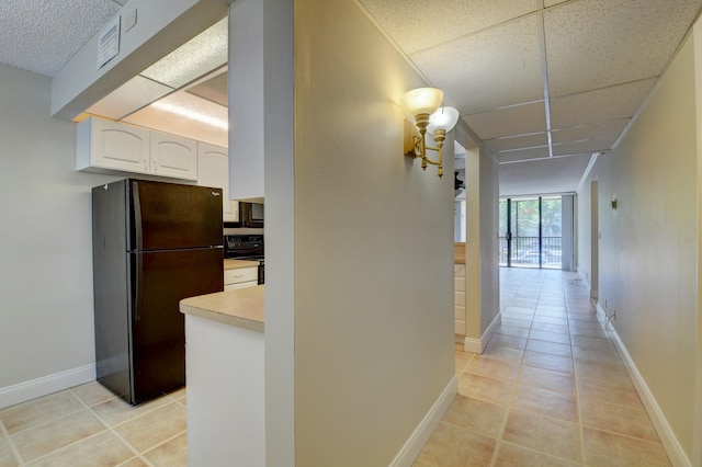 hall featuring a drop ceiling and light tile patterned floors