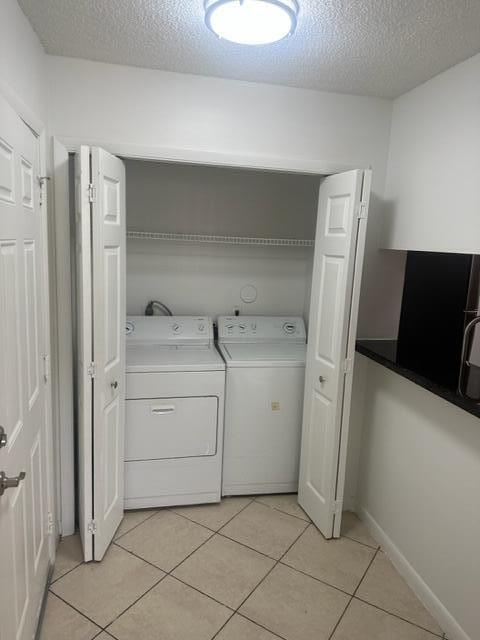 laundry room featuring a textured ceiling, separate washer and dryer, and light tile patterned floors