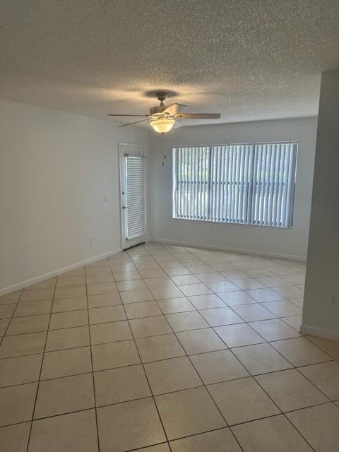 tiled spare room with a textured ceiling and ceiling fan