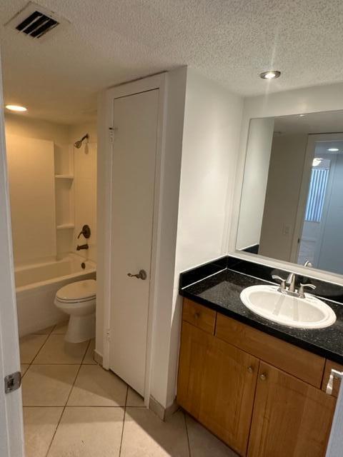 full bathroom with tile patterned flooring, a textured ceiling, tub / shower combination, vanity, and toilet