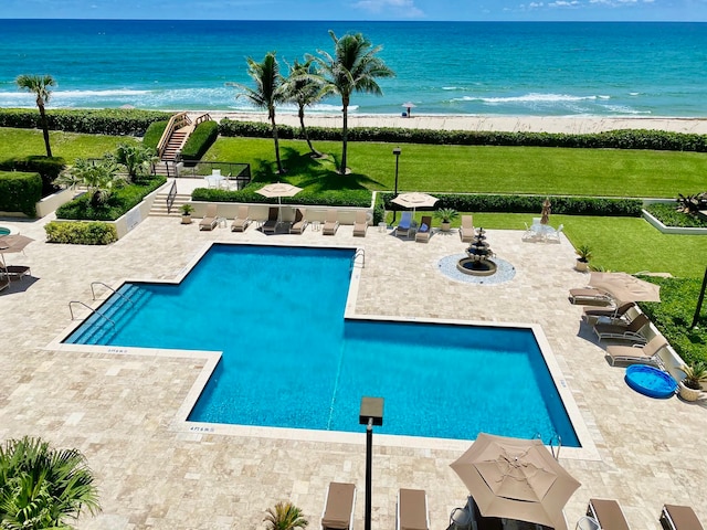 view of swimming pool with a patio area, a water view, and a beach view