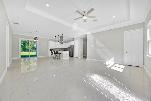 unfurnished living room with ceiling fan, a tray ceiling, and ornamental molding