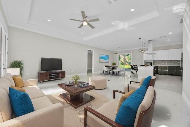 living room featuring ornamental molding, ceiling fan, and a raised ceiling