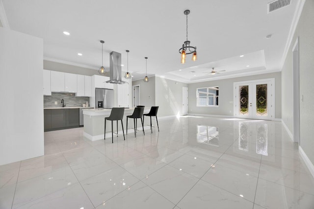 living room featuring a tray ceiling, ceiling fan, crown molding, and sink