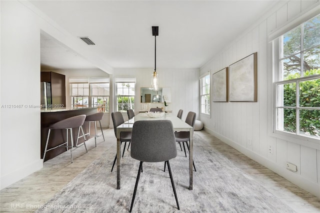 dining space featuring a wealth of natural light, beam ceiling, and light wood-type flooring