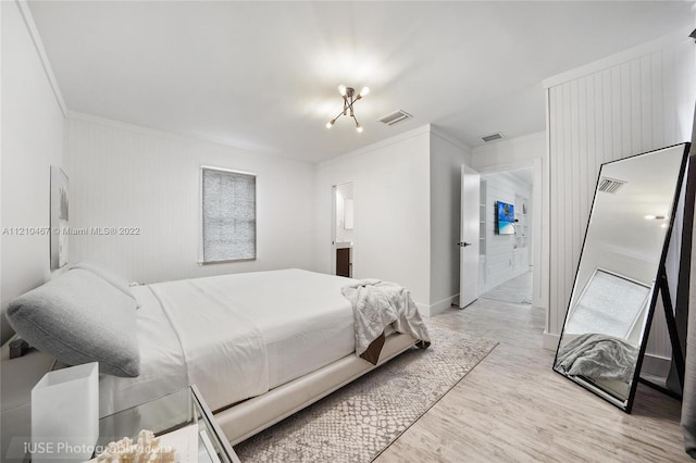 bedroom featuring connected bathroom, light hardwood / wood-style floors, and crown molding