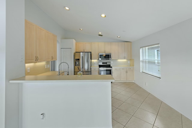 kitchen featuring kitchen peninsula, appliances with stainless steel finishes, sink, light tile patterned floors, and lofted ceiling