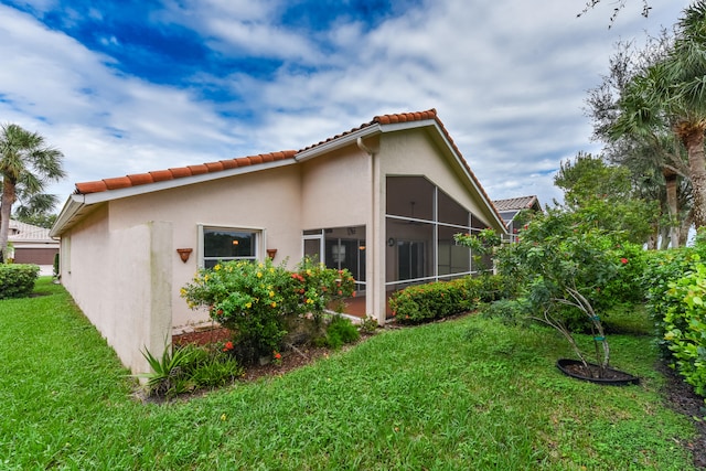 view of property exterior with a sunroom and a yard