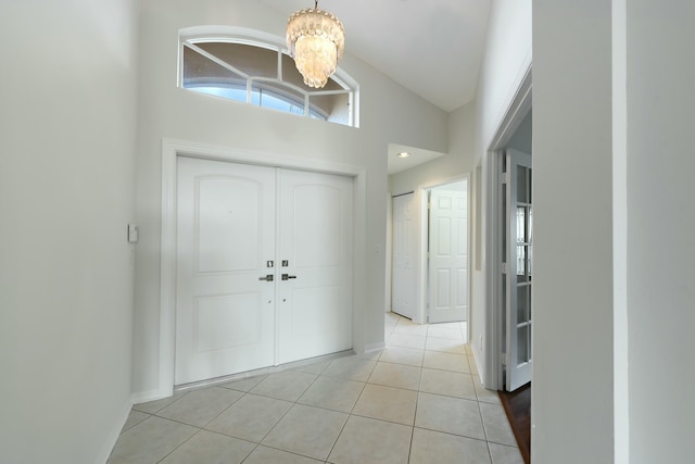 foyer featuring high vaulted ceiling, a notable chandelier, and light tile patterned flooring