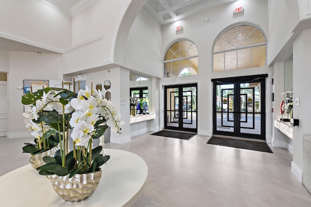 entryway featuring beam ceiling, french doors, coffered ceiling, a high ceiling, and ornamental molding