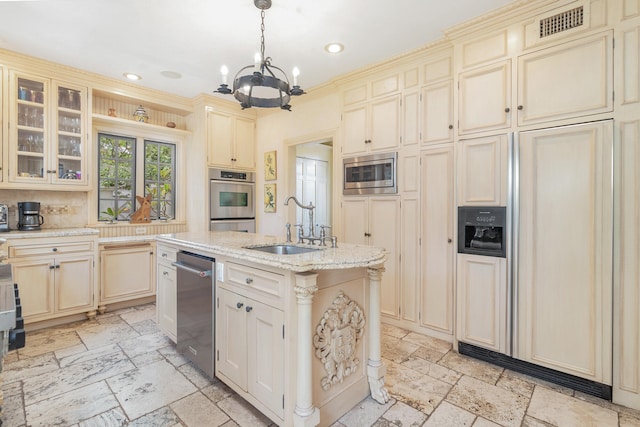 kitchen featuring cream cabinetry, hanging light fixtures, an island with sink, stainless steel appliances, and sink