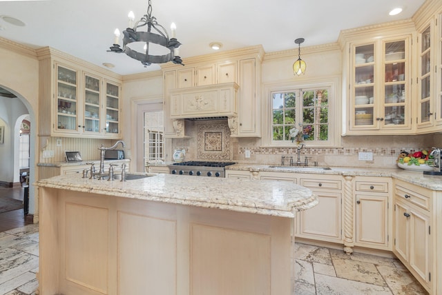 kitchen featuring decorative light fixtures, an inviting chandelier, a kitchen island with sink, and sink