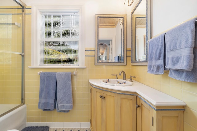 bathroom with shower / bath combination with glass door, vanity, and tile walls