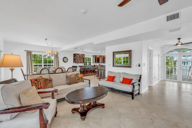 living room with french doors and ceiling fan with notable chandelier