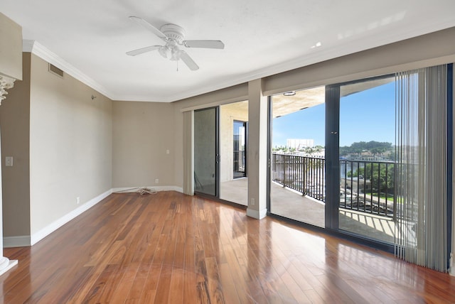 unfurnished room featuring ceiling fan, a water view, wood-type flooring, and ornamental molding