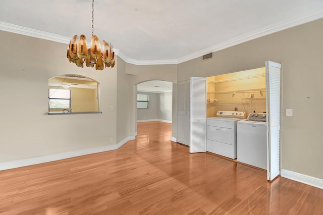 washroom featuring wood-type flooring, crown molding, washer and clothes dryer, and a notable chandelier