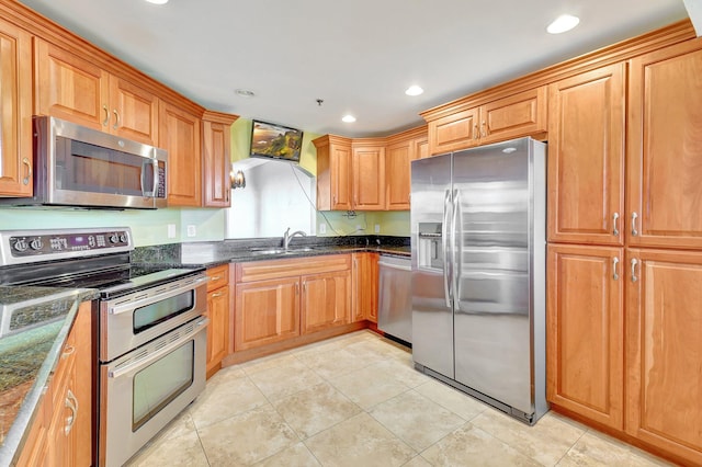 kitchen with dark stone counters, sink, light tile patterned floors, and stainless steel appliances