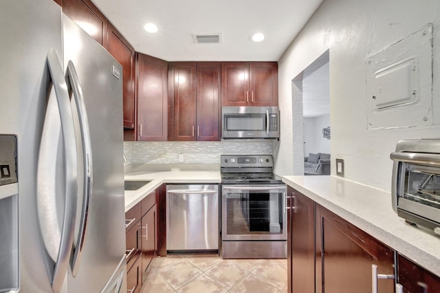 kitchen featuring appliances with stainless steel finishes, backsplash, and light stone counters