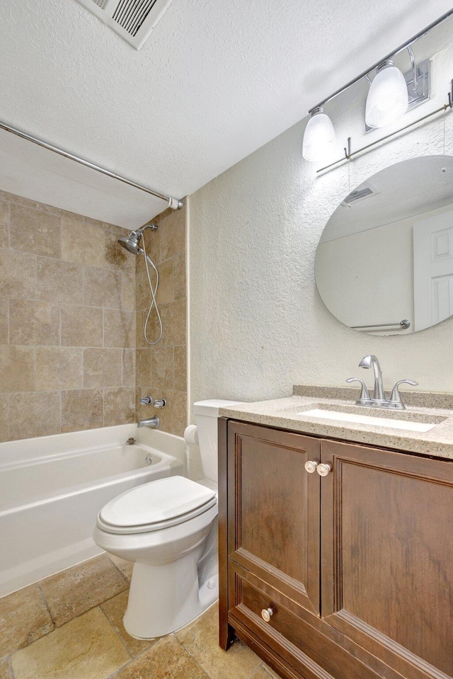 full bathroom featuring a textured ceiling, tiled shower / bath combo, vanity, and toilet